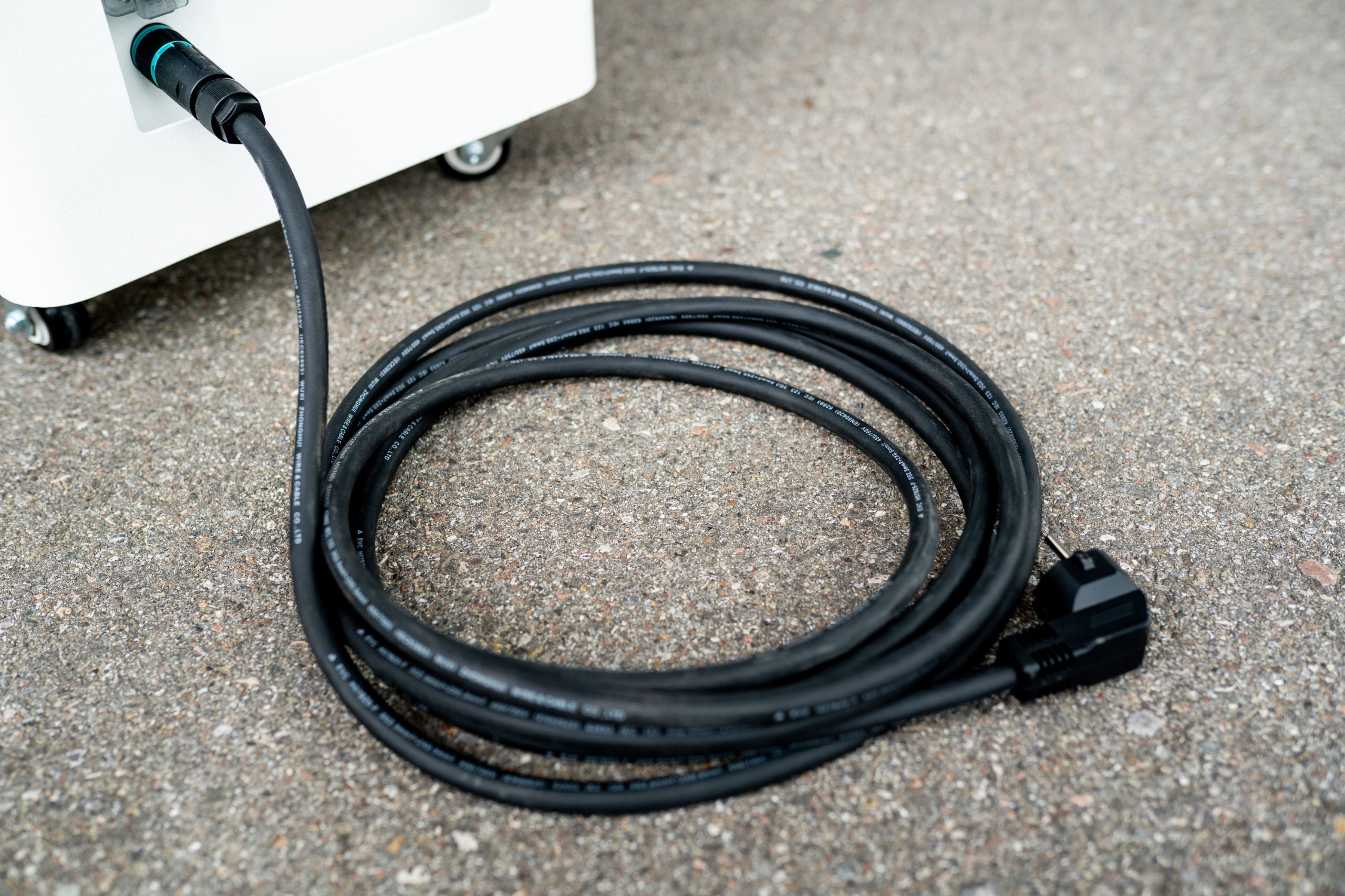 YOUL Produkt: Schwarzes, aufgerolltes Kabel auf Betonoberfläche