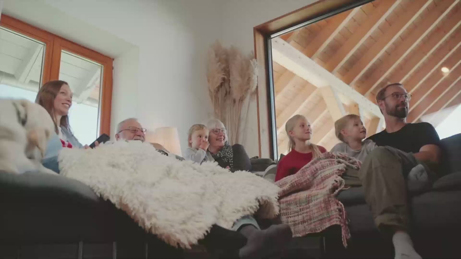 Video zeigt eine Famlie beim Fernsehen im Wohnzimmer, beim Kochen und Essen und beim Staubsaugen, es wird also Strom verbraucht. Im Flur bzw in der offenen Küche steht ein YOULIQ Batteriespeicher, der die Familie mit gespeichertem Strom ihrer PV-Anlage versorgt. 