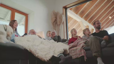 Video zeigt eine Famlie beim Fernsehen im Wohnzimmer, beim Kochen und Essen und beim Staubsaugen, es wird also Strom verbraucht. Im Flur bzw in der offenen Küche steht ein YOULIQ Batteriespeicher, der die Familie mit gespeichertem Strom ihrer PV-Anlage versorgt. 