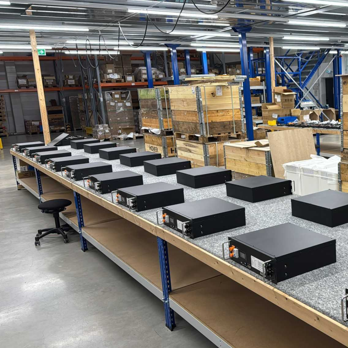 Blick in die Fertigung des YOULIQ one Mehrere Batteriemodule des 10 kWh Speichers sind für die Endmontage und Qualitätssicherung in der deutschen Produktionshalle aufgereiht.